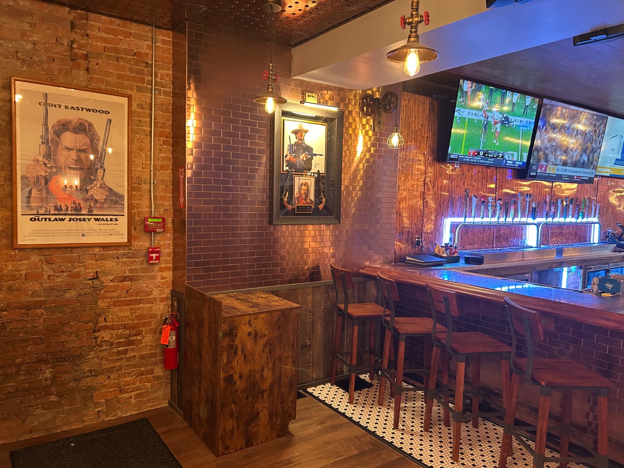 Bar area with exposed brick walls, Western movie posters, and TV screens