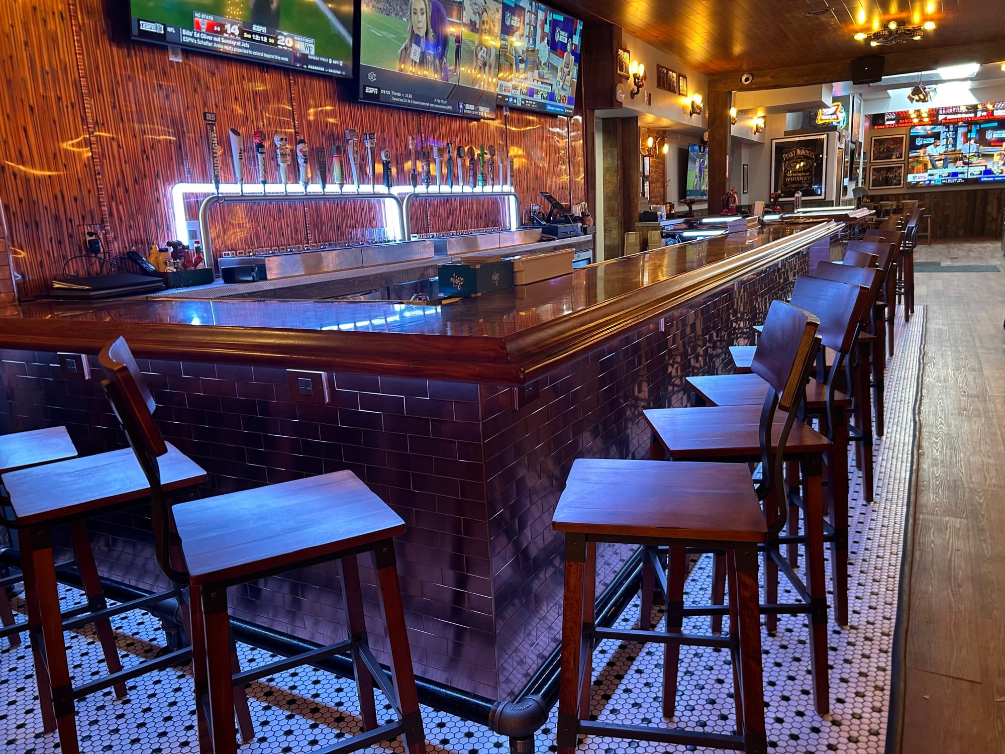 Modern bar with extensive beer tap selection, wooden counter, and tile base
