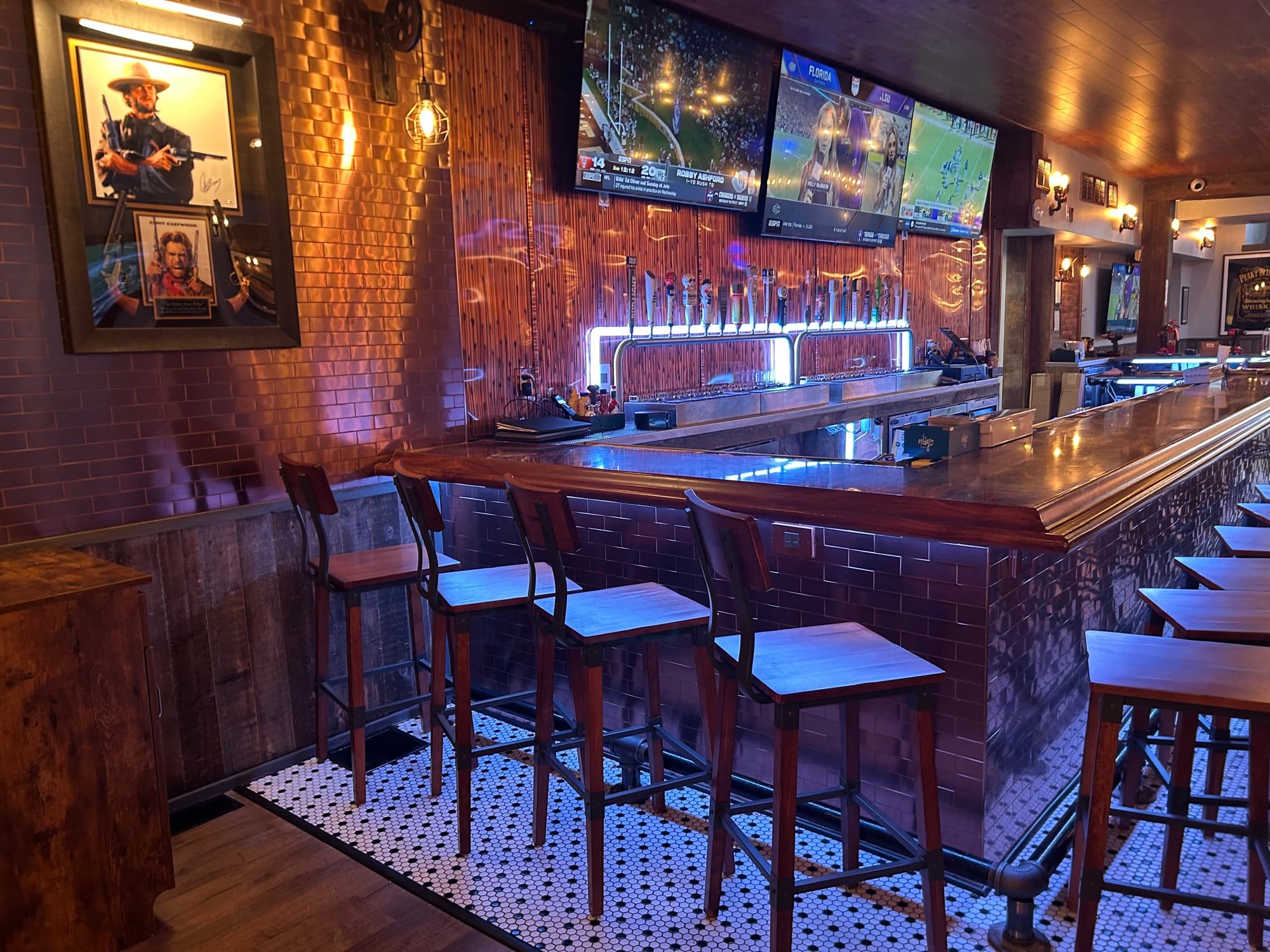 Bar with multiple beer taps, bar stools, and TVs displaying sports