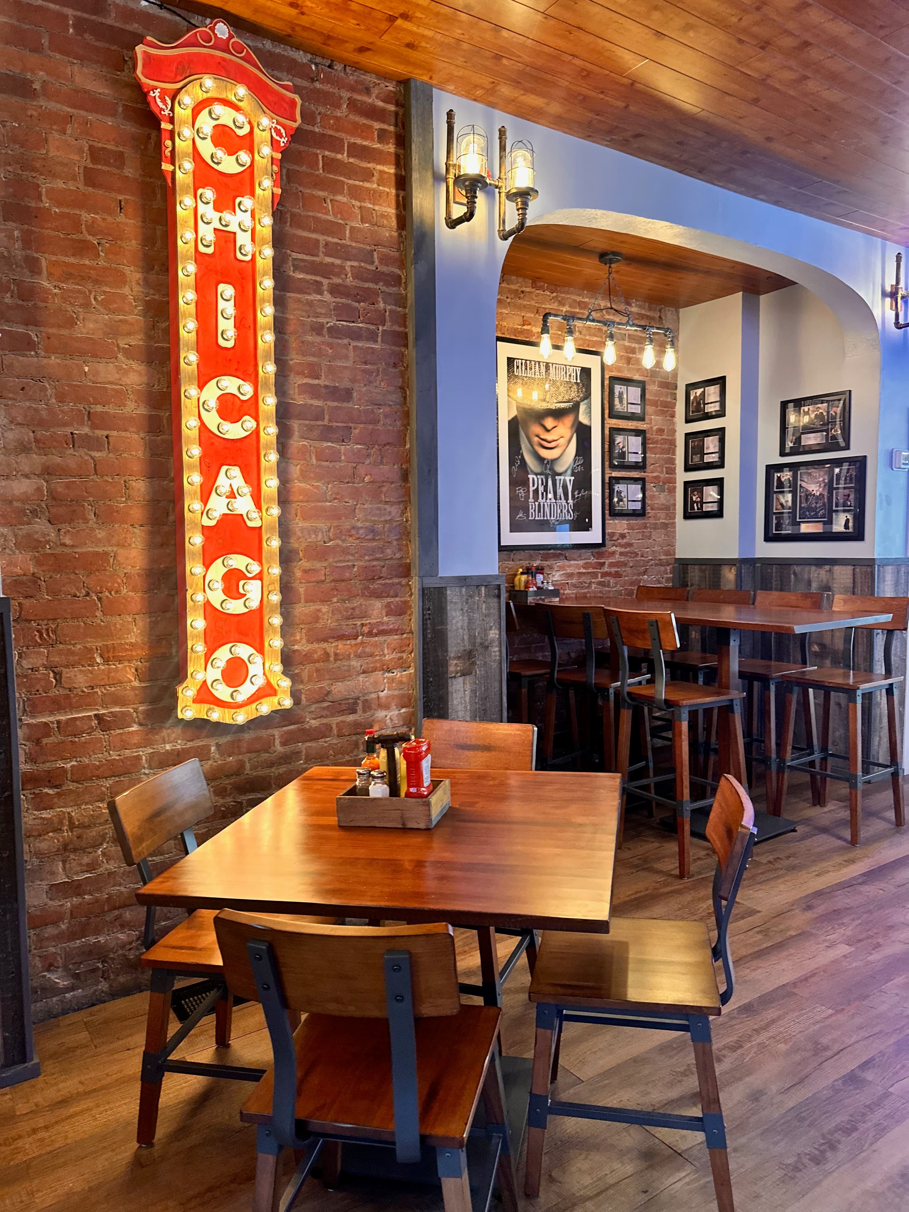 Chicago marquee sign with light bulbs on exposed brick wall above dining table