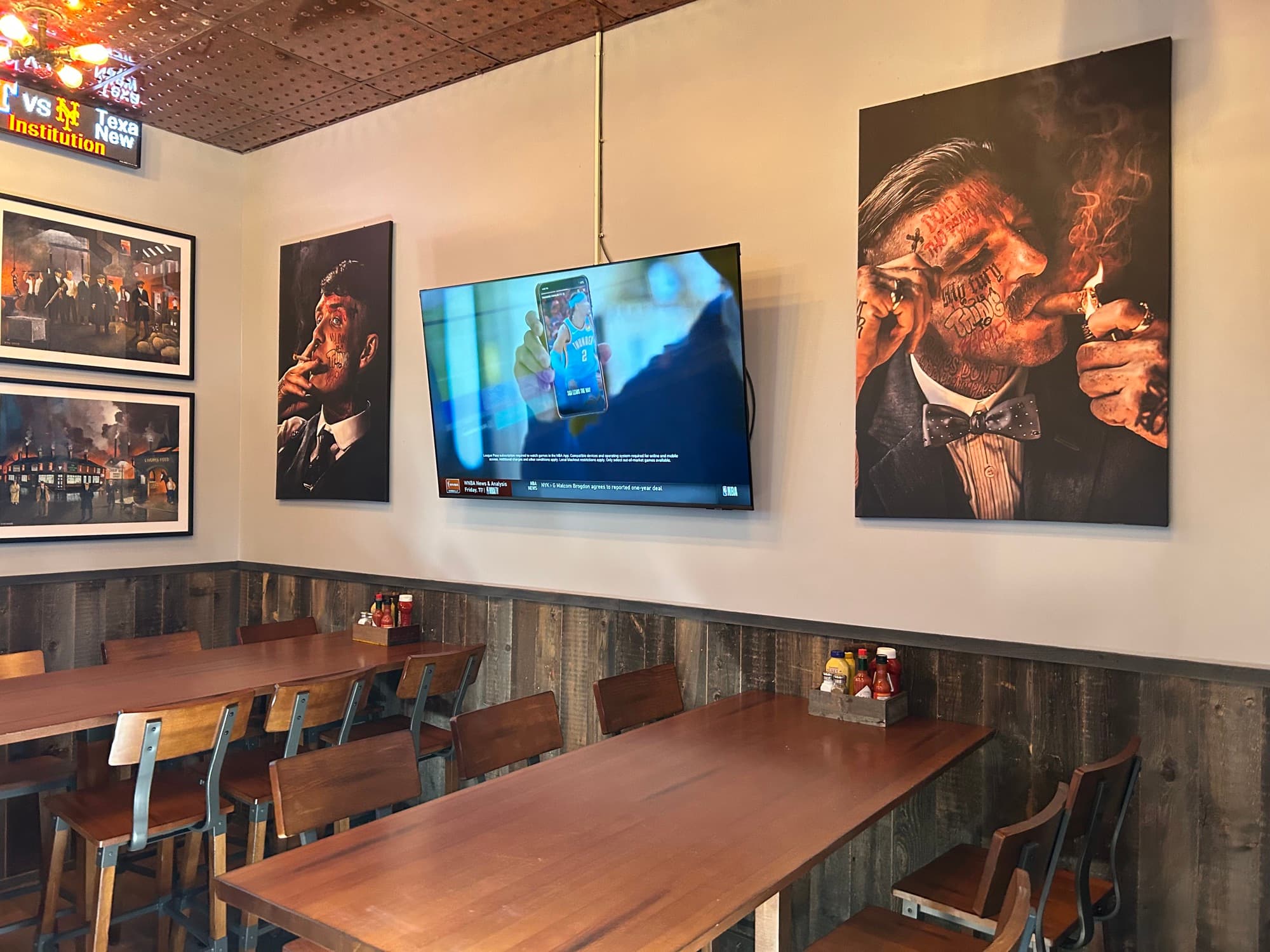 Dining area with wooden tables and vintage-style wall art at CJ'S Sandwich Institution