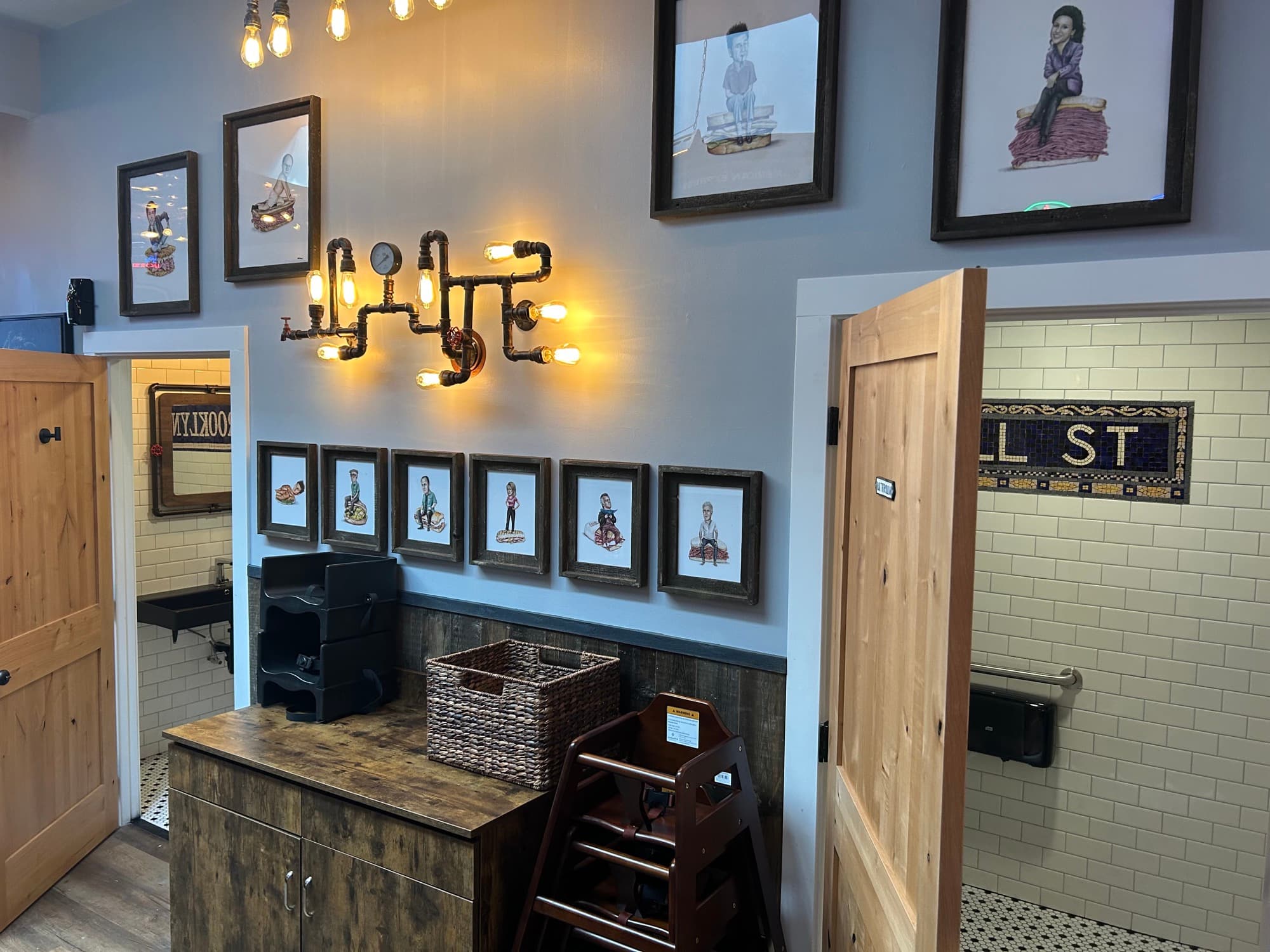 Waiting area with industrial pipe light fixture, framed artwork, and restroom entrance