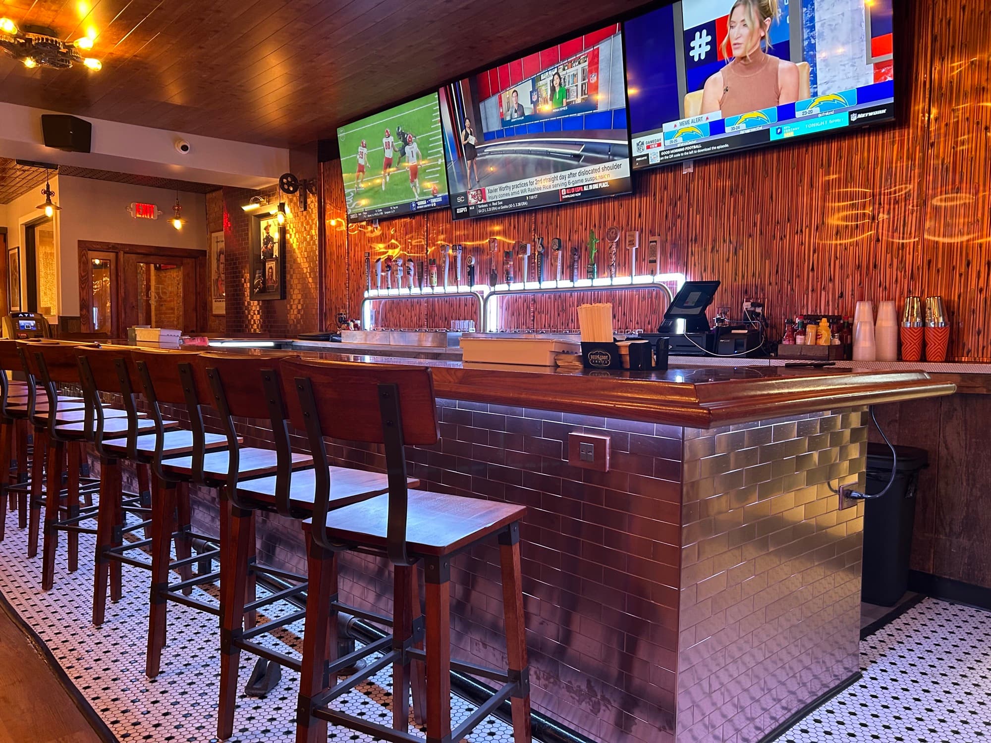 Bar with wooden counter, tap handles, and multiple TV screens showing sports