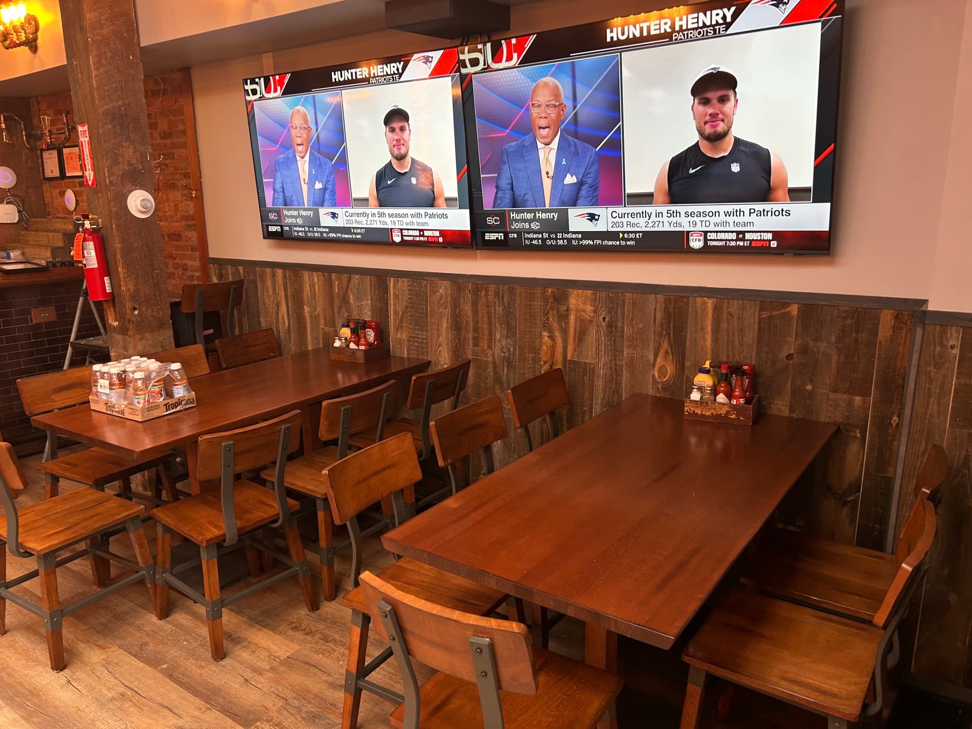 Restaurant dining area with wooden tables and ESPN Patriots coverage on large TV screen