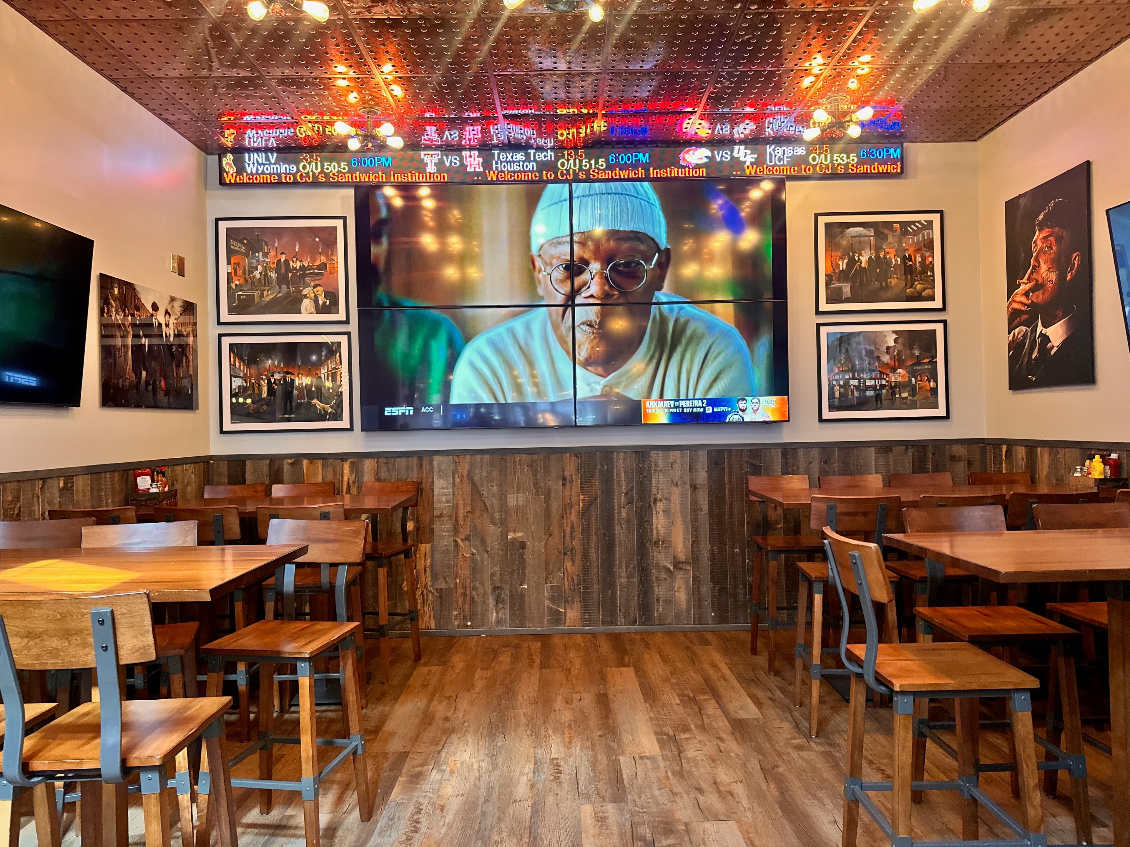 Dining room with wooden tables, framed photos, LED ticker, and large ESPN sports screen