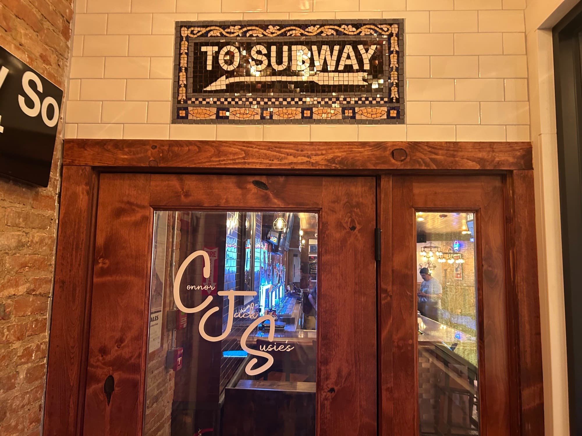 Mosaic tile sign reading 'TO SUBWAY' above wooden doors at entrance