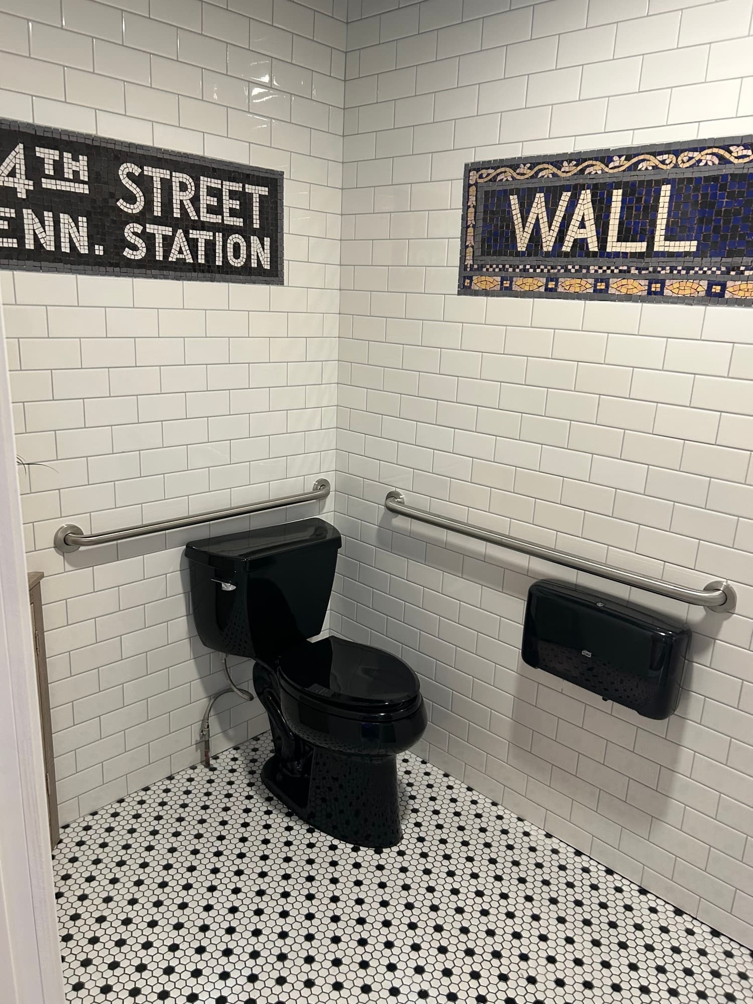 Bathroom with white subway tile, Wall Street mosaic sign, and Pennsylvania Station sign